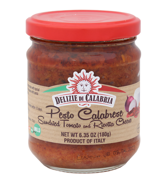 A jar of Pesto Calabrese with a red label, produced by Delizie Di Calabria, showing images of sundried tomatoes and pumpkin seeds, indicating the flavors of the pesto.