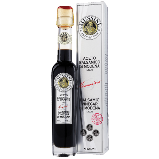 A bottle of Mussini Balsamic Vinegar di Modena with a white label, red cap, and branding details, placed next to its packaging box.