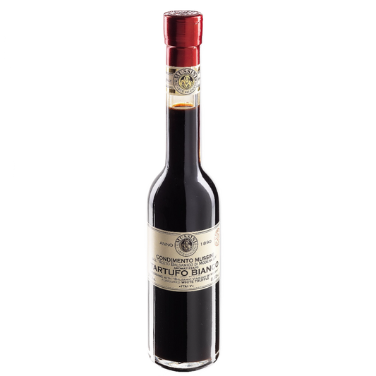 A bottle of Mussini White Truffle Flavored Balsamic Vinegar with a red cap on a white background.