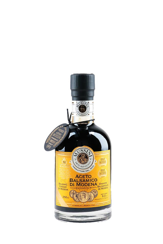 Bottle of balsamic vinegar with a yellow label on a white background