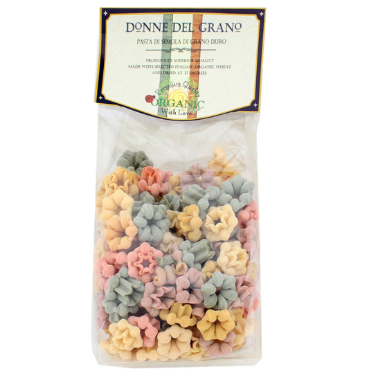 Packaged Donne Del Grano organic colored pasta, displaying a variety of shapes and colors such as green, yellow, red, and beige.