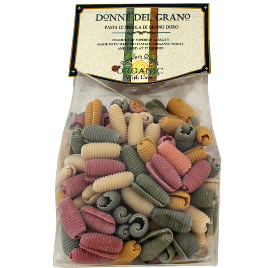 Packaged organic pasta branded as Donne Del Grano, featuring a variety of colored noodles visible through the clear packaging, labeled as 'Paguri' colored pasta.